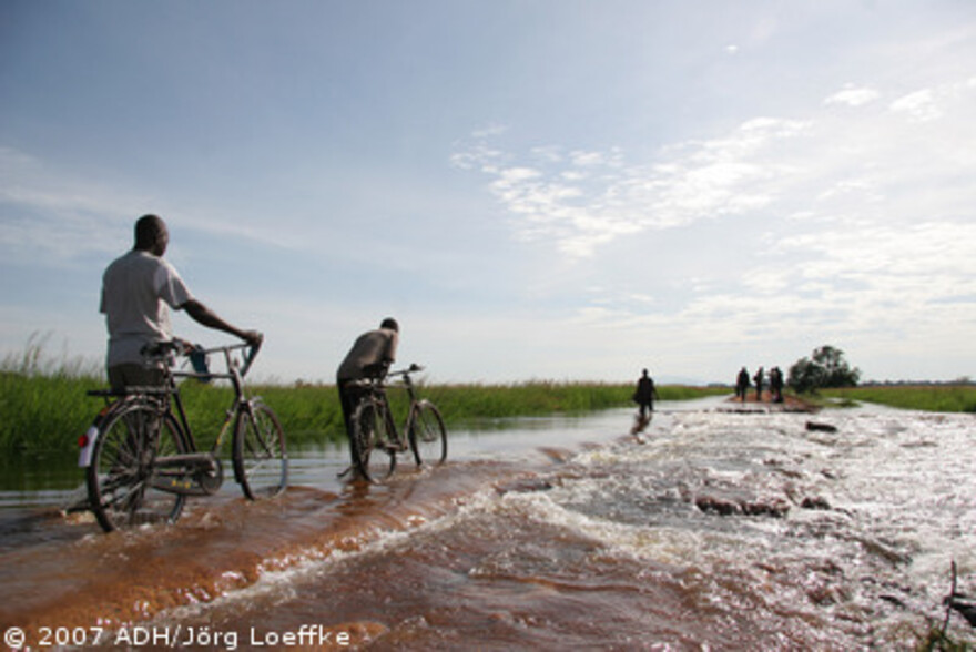 Flut Afrika: Radfahrer schieben ihre Fahrräder durch das Hochwasser
