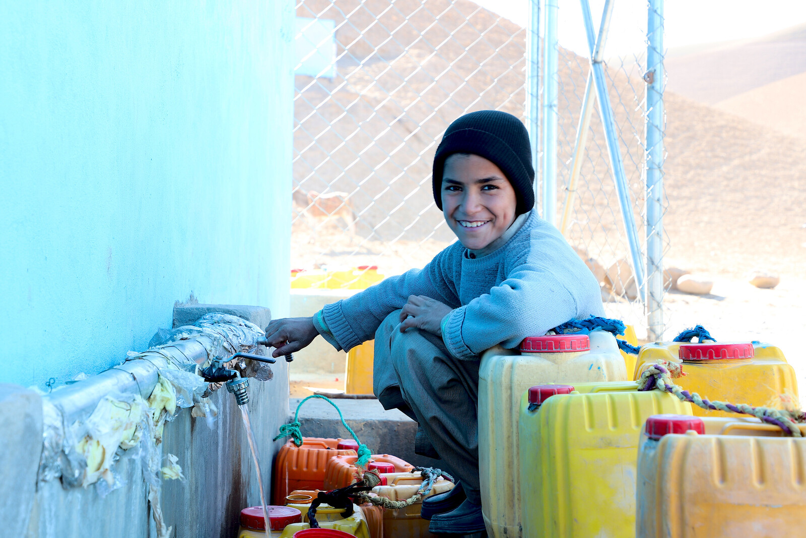 Ein Junge in Afghanistan füllt sich Trinkwasser in gelbe Kanister ab