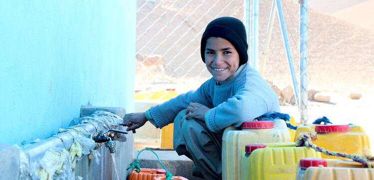 Ein Junge in Afghanistan füllt sich Trinkwasser in gelbe Kanister ab Ein Junge in Afghanistan füllt sich Trinkwasser in gelbe Kanister ab