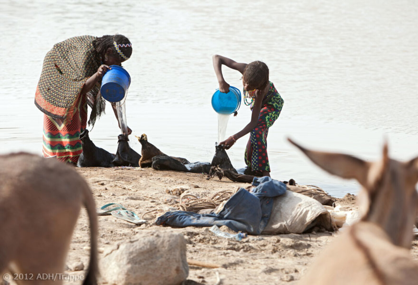 Unweit sind zwei Mädchen dabei, Ziegenhäute mit Wasser zu befüllen.