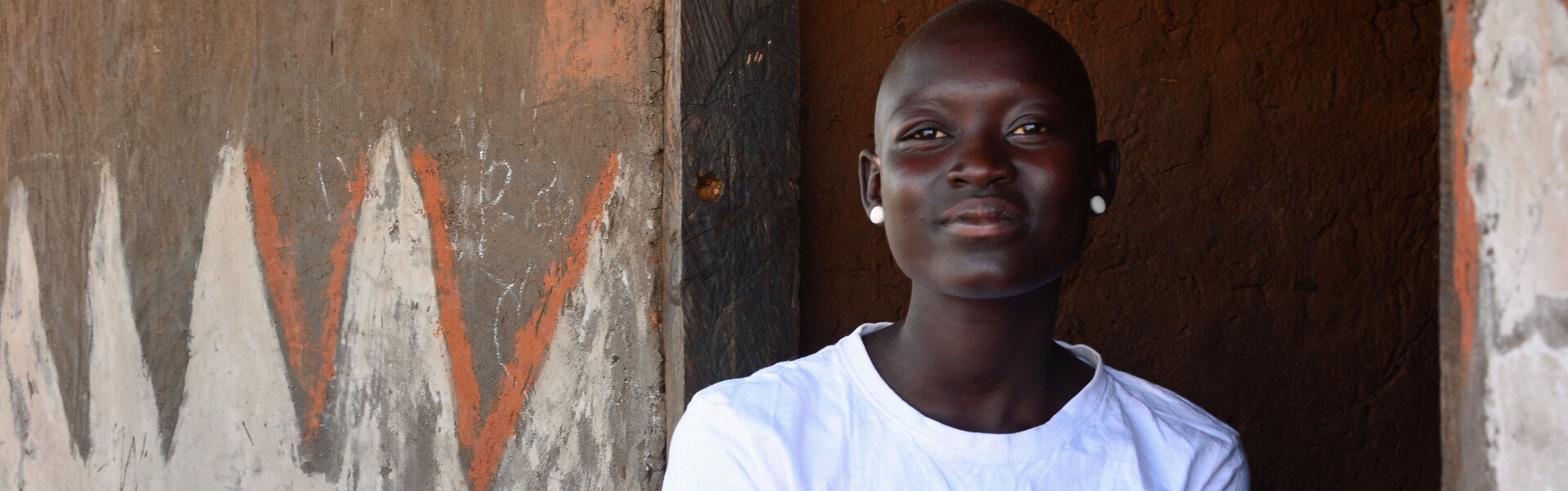 Eine Helferin von der Bündnisorganisation AWO International sitzt vor einem Haus in Uganda 