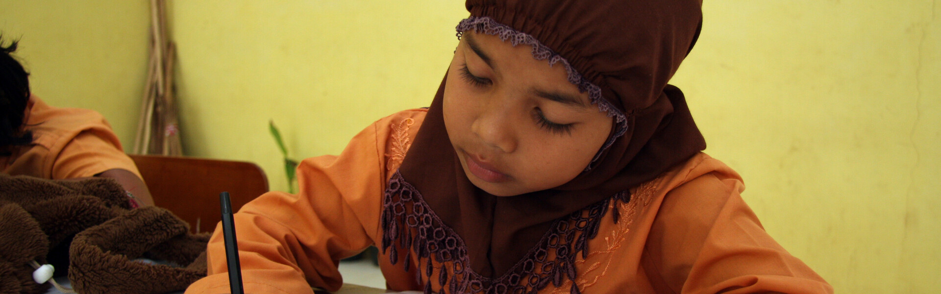 In Indonesien können viele Kinder nicht in die Schule gehen. Ein Mädchen lernt schreiben und lesen in der Grunschule.