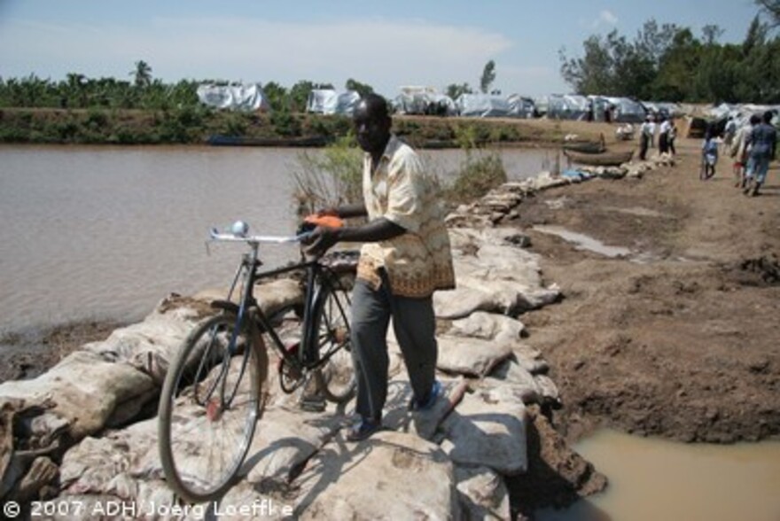 Flut Afrika: Mann schiebt Fahrrad über Sandsäcke