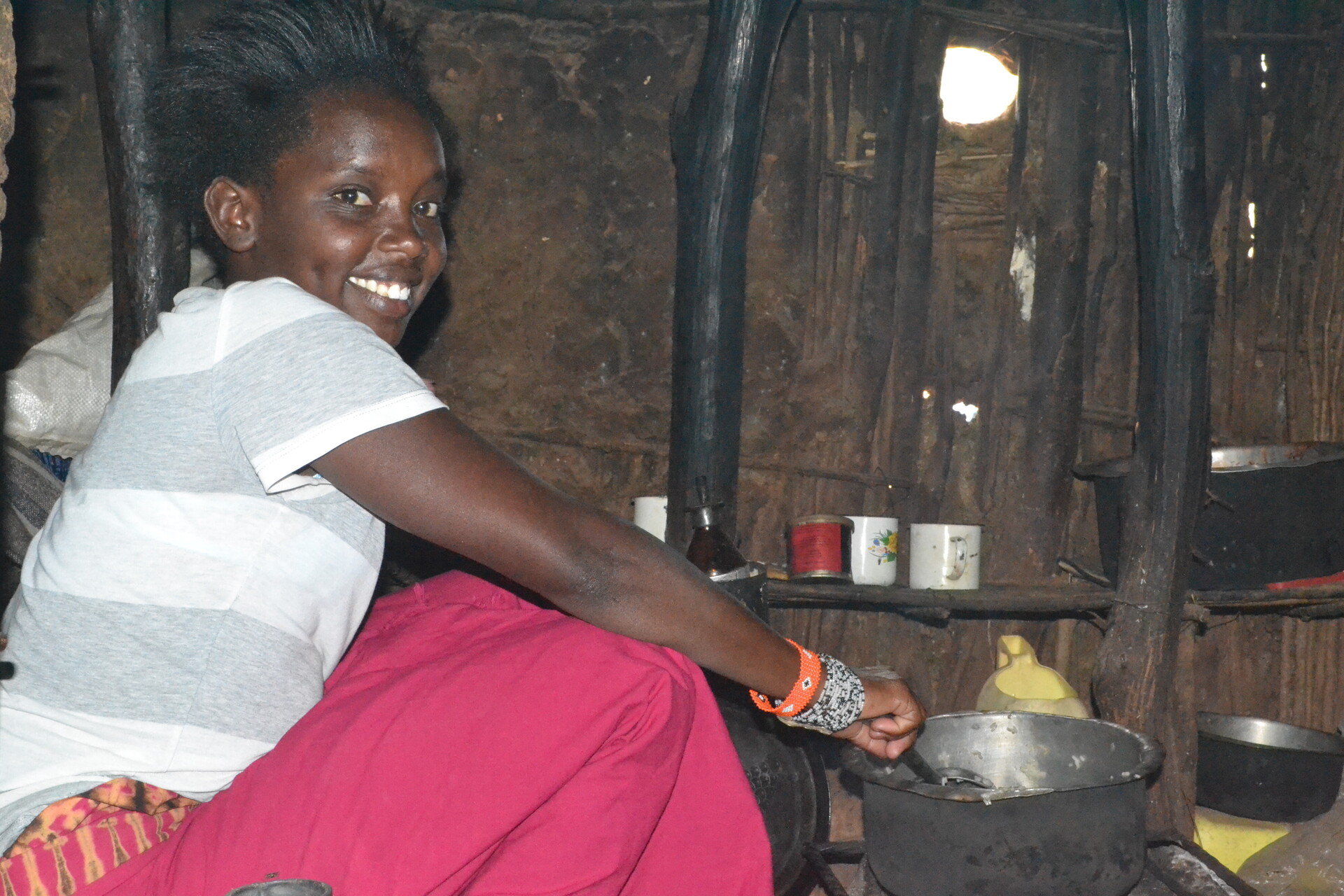 Janet lächelt in die Kamera und kocht Reis in ihrem Haus in Kenia. Janet lächelt in die Kamera und kocht Reis in ihrem Haus in Kenia.