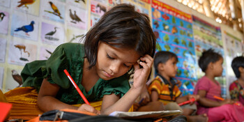 Ein Mädchen in einer Schule in Bangladesch löst Aufgaben in einem Buch