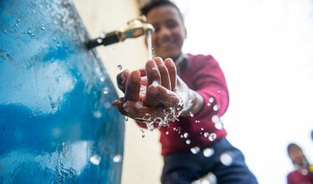Ein Junge in einer Grundschule in Nepal freut sich über sauberes Trinkwasser 