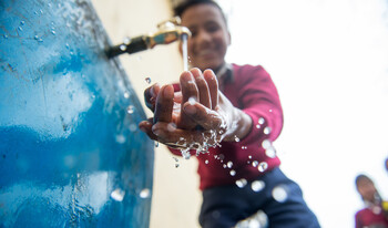 Ein Junge in einer Grundschule in Nepal freut sich über sauberes Trinkwasser 