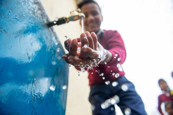 Ein Junge in einer Grundschule in Nepal freut sich über sauberes Trinkwasser 