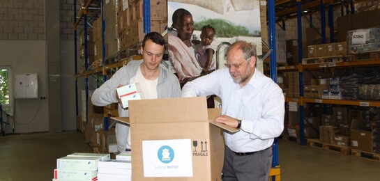 In einem Lager packen Bernd Pastors und ein Helfer Pakete für Flüchtlinge im Mittelmeer.