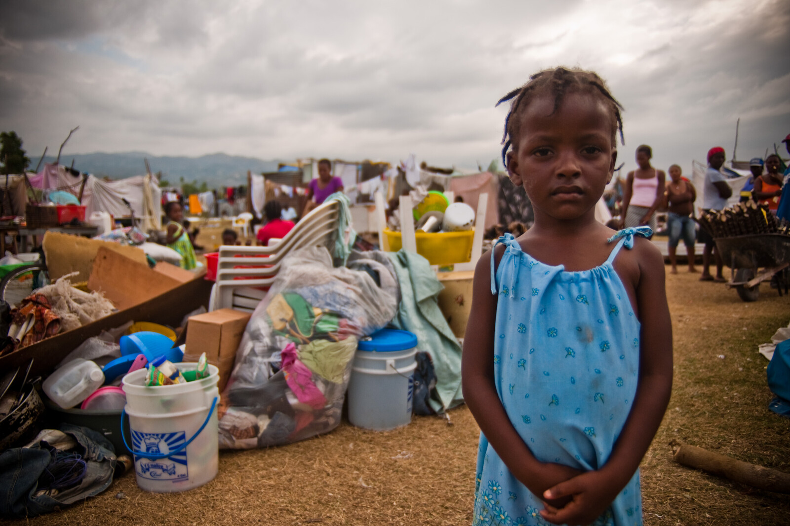 Ein Mädchen steht vor Zelten in Haiti.