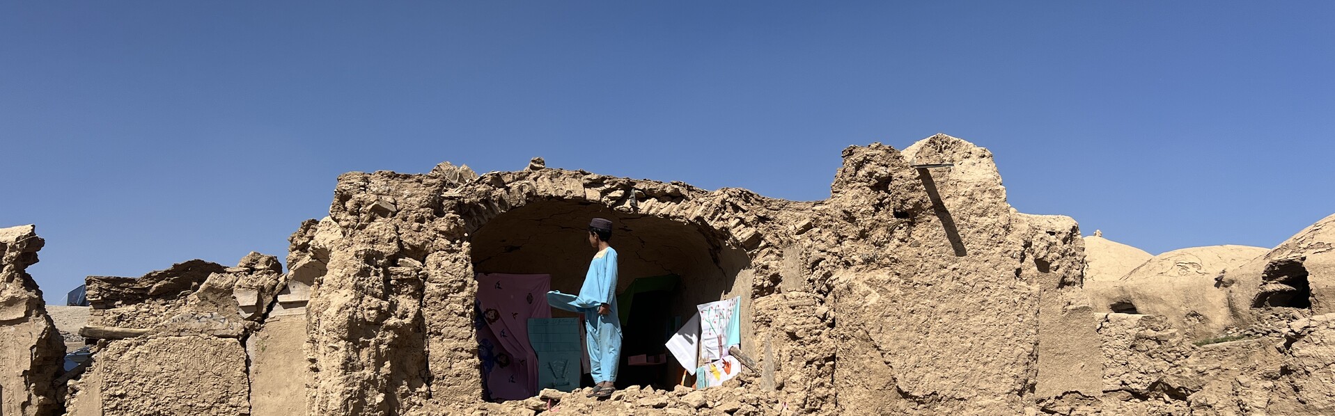 Ein Junge steht vor den Überresten eines Hauses, das bei einem Erdbeben in Afghanistan zerstört wurde (Symbolbild)