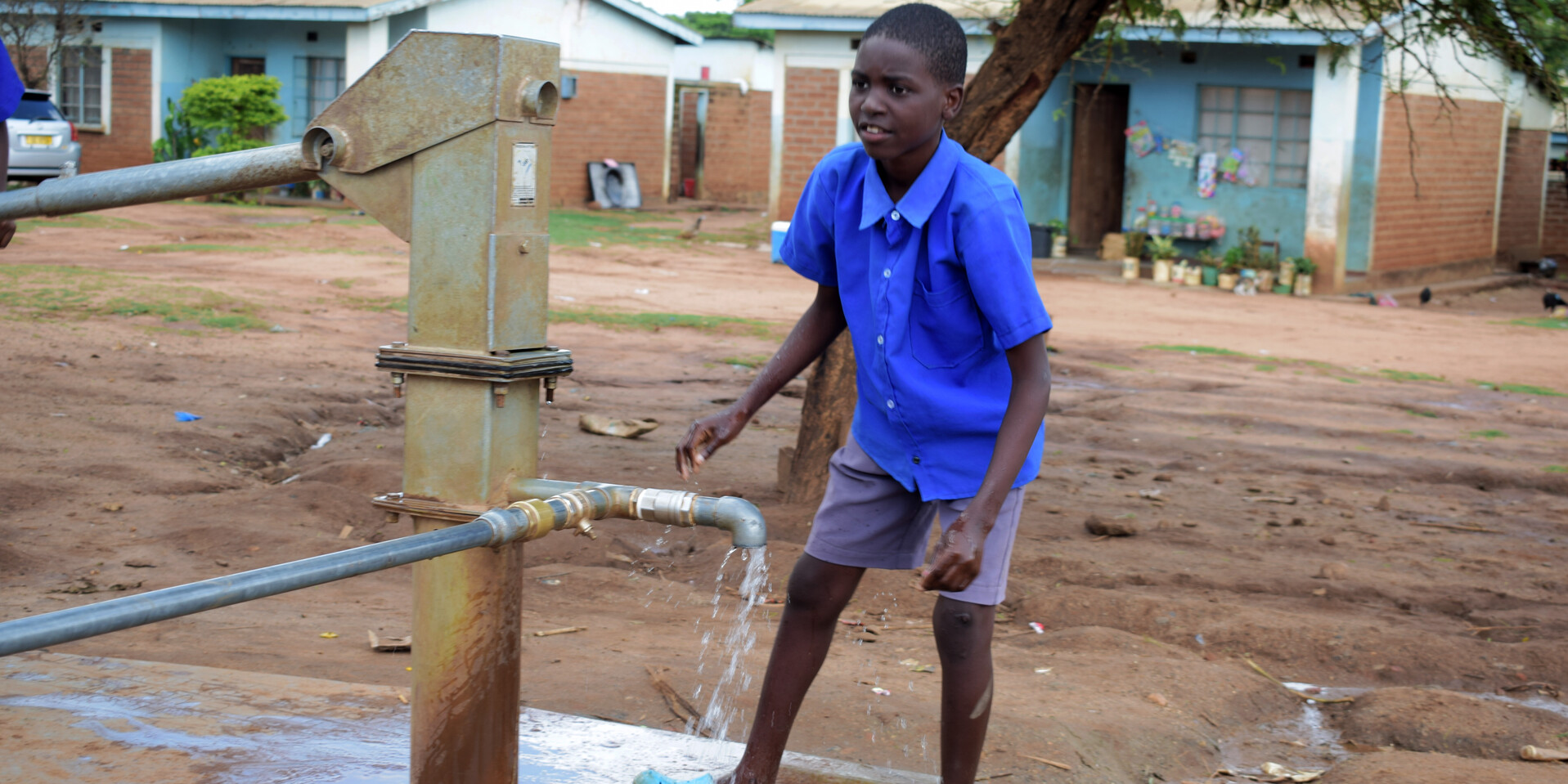 Der Schüler Kelvin wäscht sich am Wasserhahn des neu errichteten Brunnens auf dem Mtsiliza-Schulgelände in Malawi seine Hände Der Schüler Kelvin wäscht sich am Wasserhahn des neu errichteten Brunnens auf dem Mtsiliza-Schulgelände in Malawi seine Hände