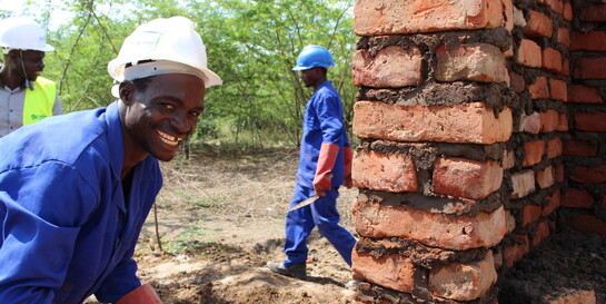 Ein Maurer baut in Malawi ein stabiles Haus aus Stein und Zement