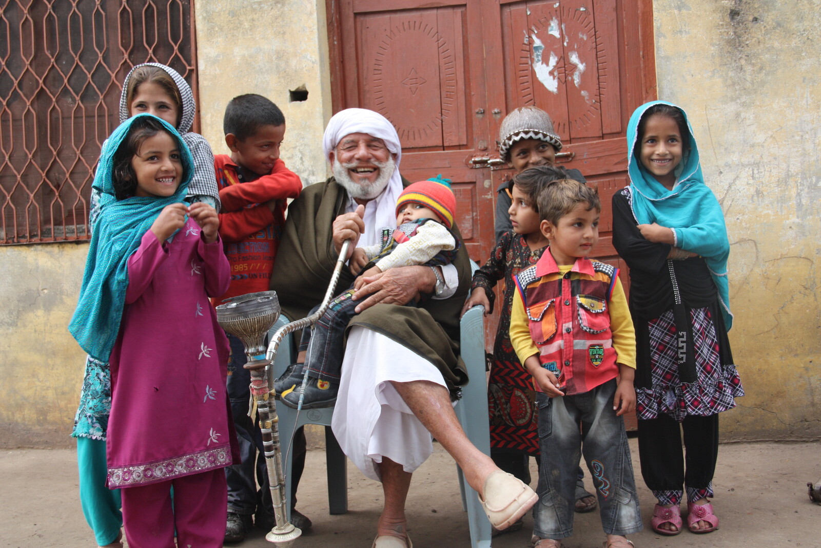 Old man is sitting on the streets surrounded by children