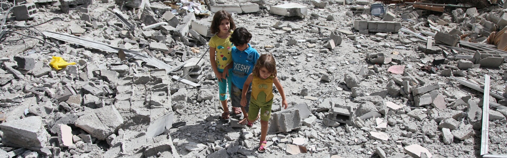 Flüchtlinge in Syrien: In einem von Krieg und Bomben betroffenen Gebiet stehen drei Kinder und schauen sich die Zerstörung an.