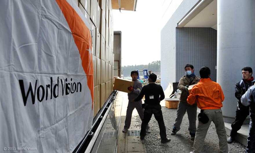 002-wagen-wird-gepackt Mitarbeiter von unserer Mitgliedsorganisation World Vision packen Kartons mit Hilfsgütern auf einen Lastwagen.