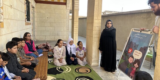 Ein lokaler Helfer klärt Kinder über die Gefahren und den richtigen Umgang mit Blindgängern und Minen auf