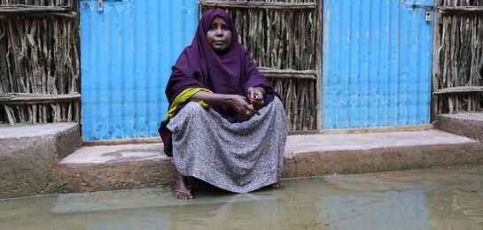 Frau in Somalia sitzt vor ihrem Haus in der Überschwemmung