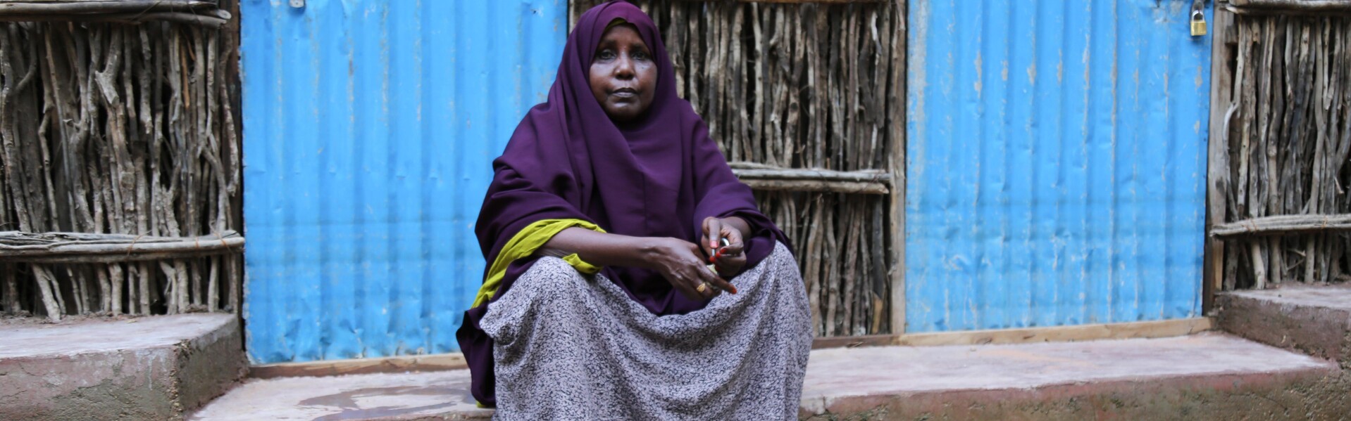 Frau in Somalia sitzt vor ihrem Haus in der Überschwemmung