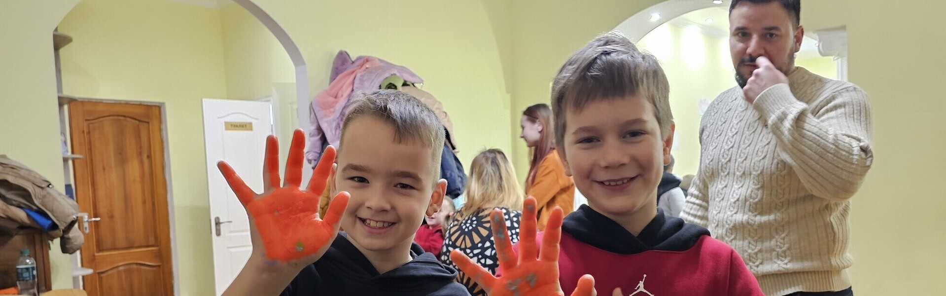 Kindernachmittag in Tschornomorsk: Kinder zeigen rot angemalte Hände in die Kamera