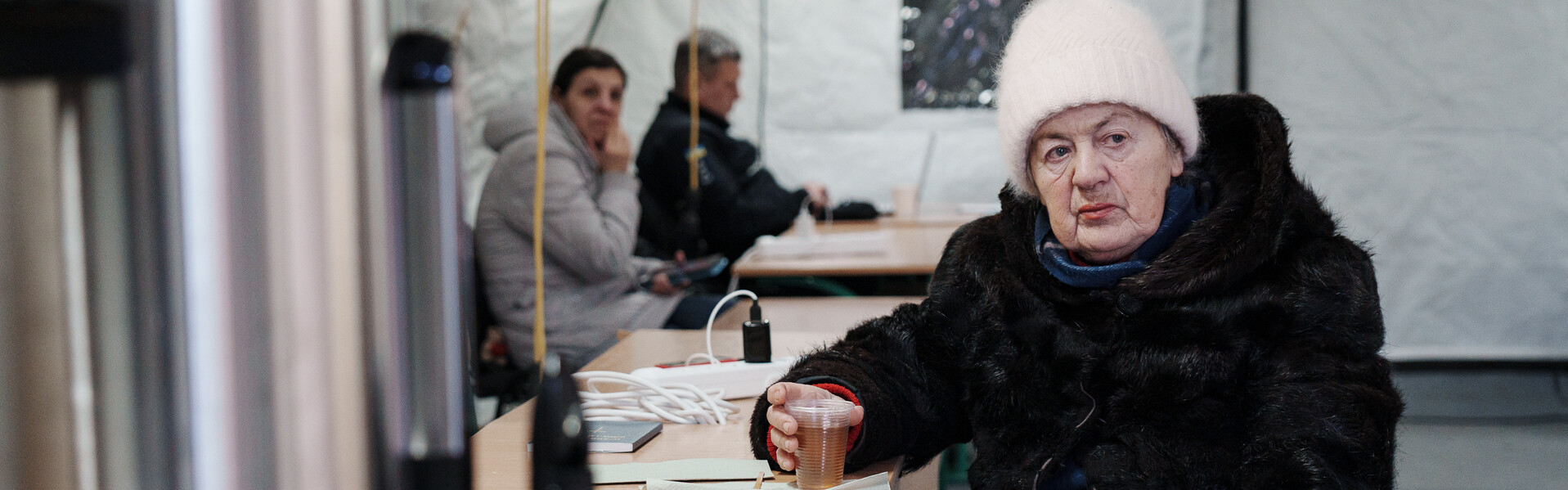 Eine Frau aus der Ukraine wärmt sich in einem Zelt auf Eine Frau aus der Ukraine wärmt sich in einem Zelt auf