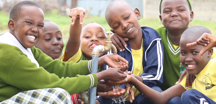 Schulkinder in Kenia freuen sich über sauberes Trinkwasser, das aus dem Brunnen kommt