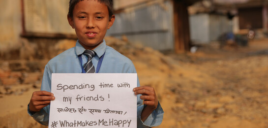 Kind h&#228;lt Zettel in der Hand mit der Aufschrift "What Makes me Happy - Spending time with friends"