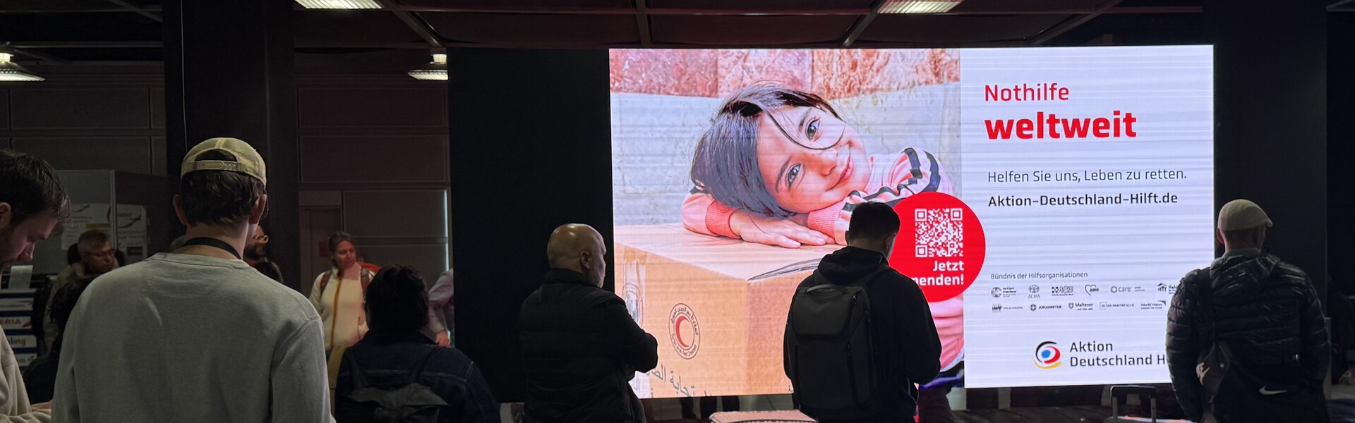 Außenwerbung von Aktion Deutschland Hilft an einem Gepäckband am Flughafen