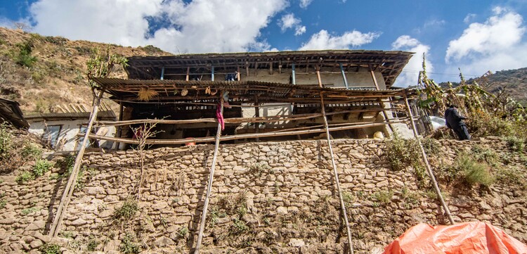Ein Lehm-Holzhaus in Nepal wird von hölzernen Pfählen abgestützt