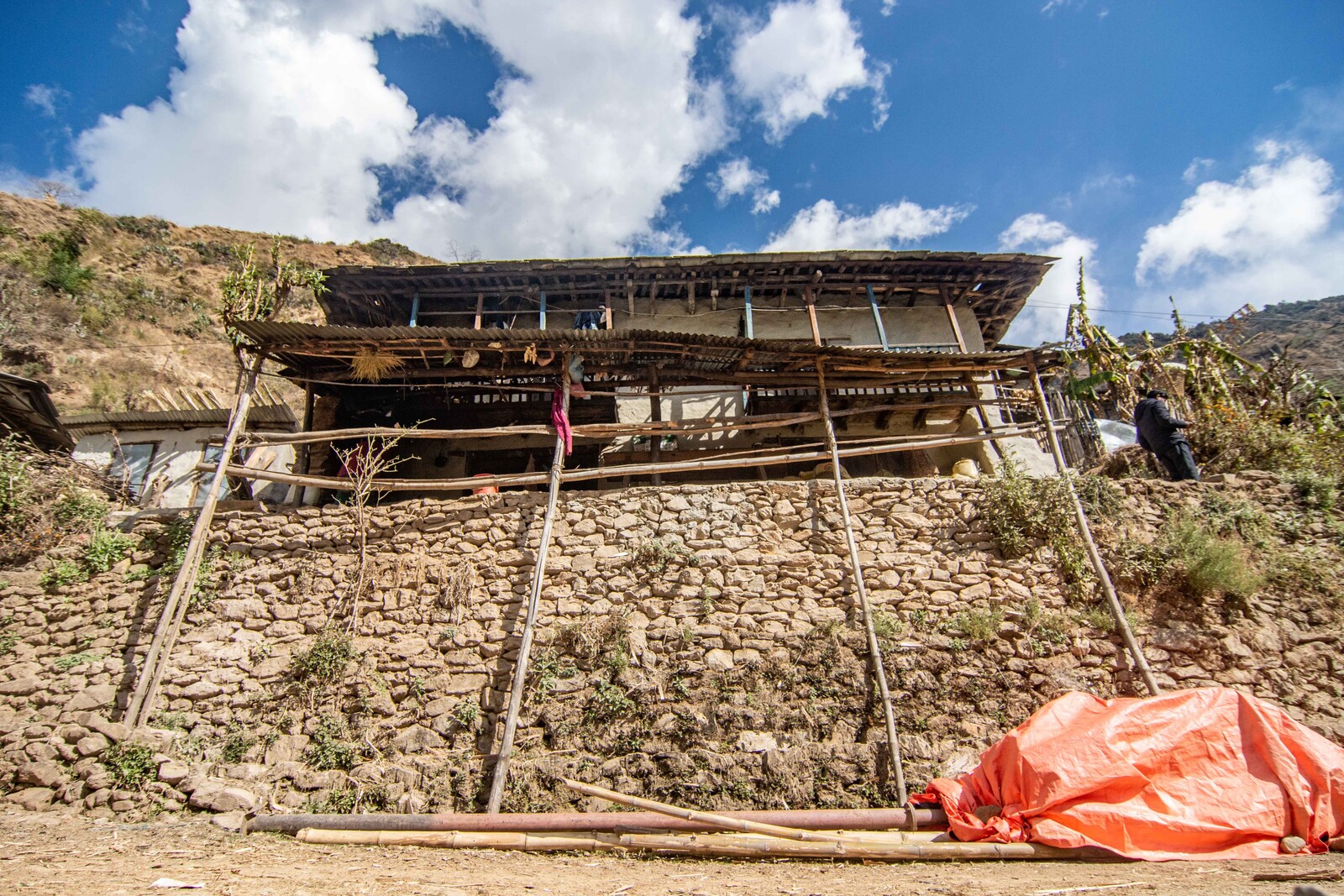 Ein Lehm-Holzhaus in Nepal wird von hölzernen Pfählen abgestützt