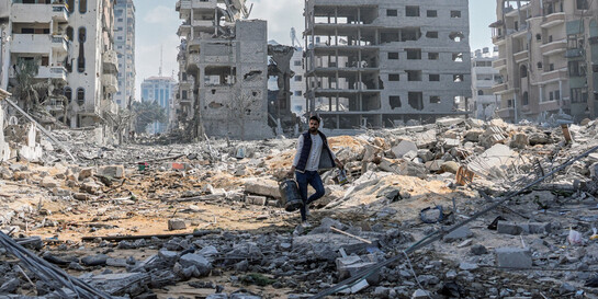 Ein Mann in Gaza umgeben von zerbombten Häusern