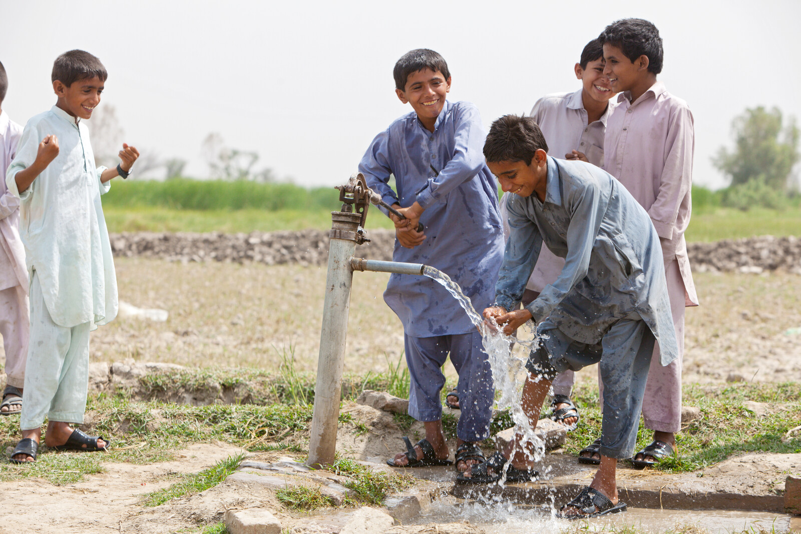 In Pakistan spielen Jungen nach dem Hochwasser an einer neuen Wasserpumpe.