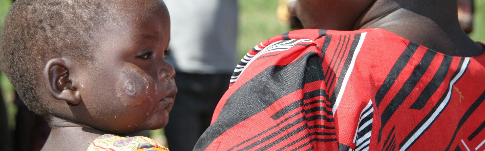 In Uganda ist die Situation für Kinder häufig schwierig, da sie unter Kämpfen in Nachbarregionen zu leiden haben. Ein Junge trägt seinen kleinen Bruder.