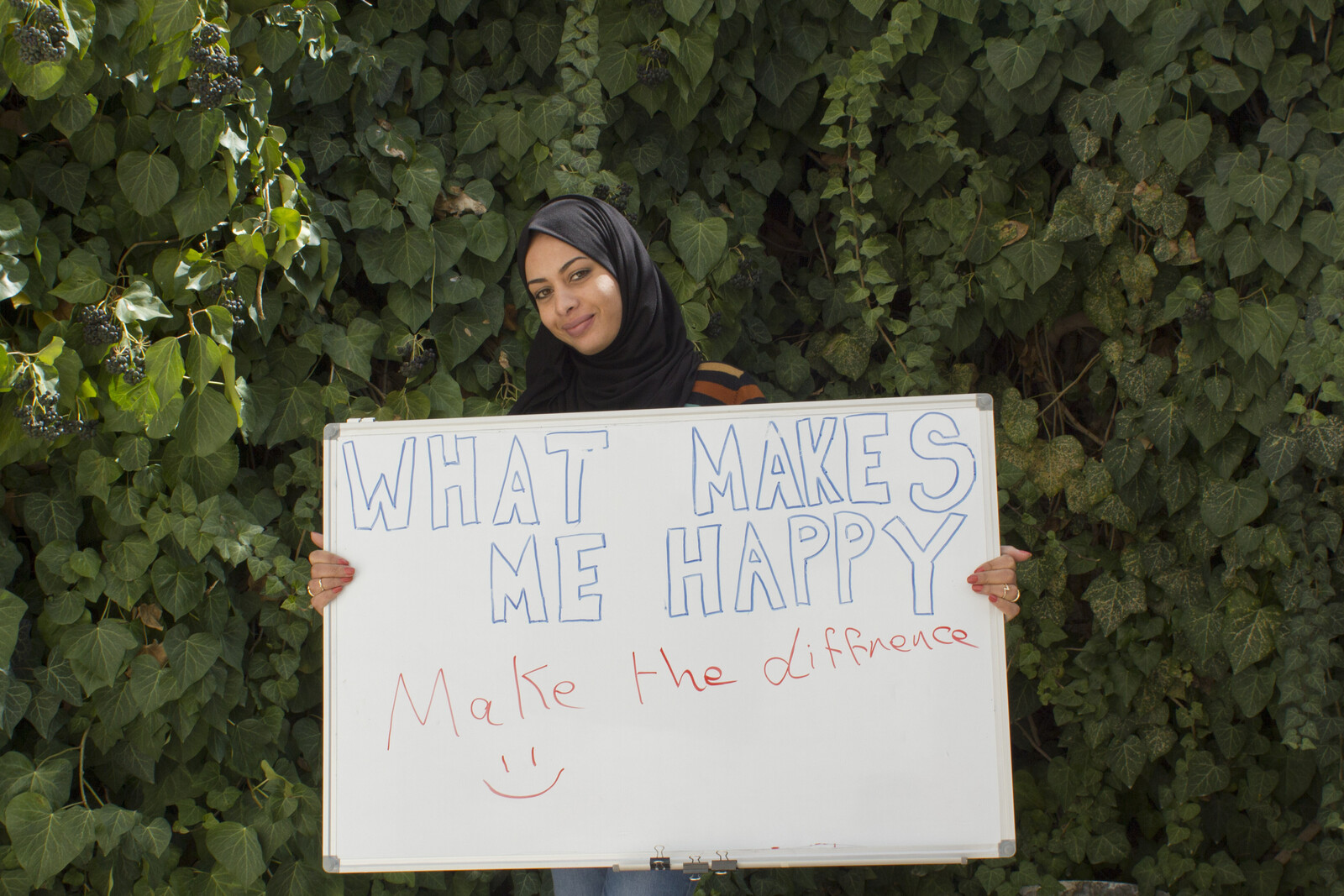 Eine Frau hält in Jordanien ein Schild hoch mit der Aufschrift "#whatmakesmehappy"