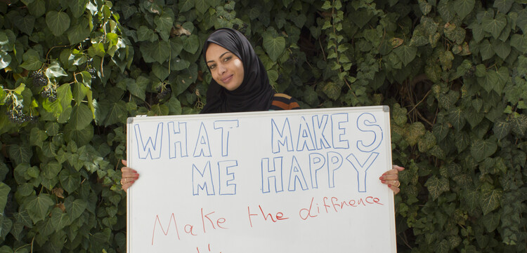 Eine Frau hält in Jordanien ein Schild hoch mit der Aufschrift "#whatmakesmehappy"