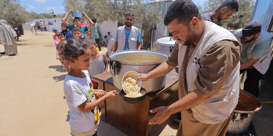 Helfer verteilt Mahlzeit an Mädchen in Gaza