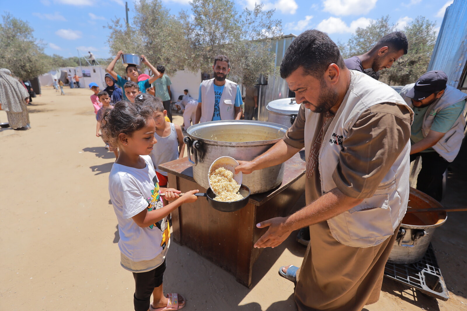 Ein Helfer verteilt Mahlzeiten an Kinder in Gaza
