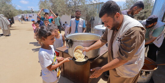 Ein Helfer verteilt Mahlzeiten an Kinder in Gaza
