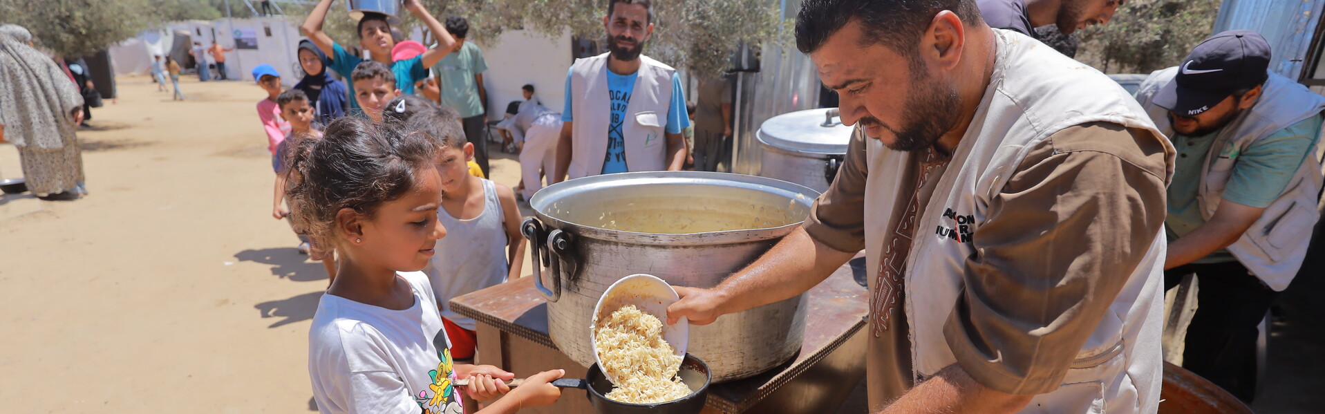 Helfer verteilt Mahlzeit an Mädchen in Gaza