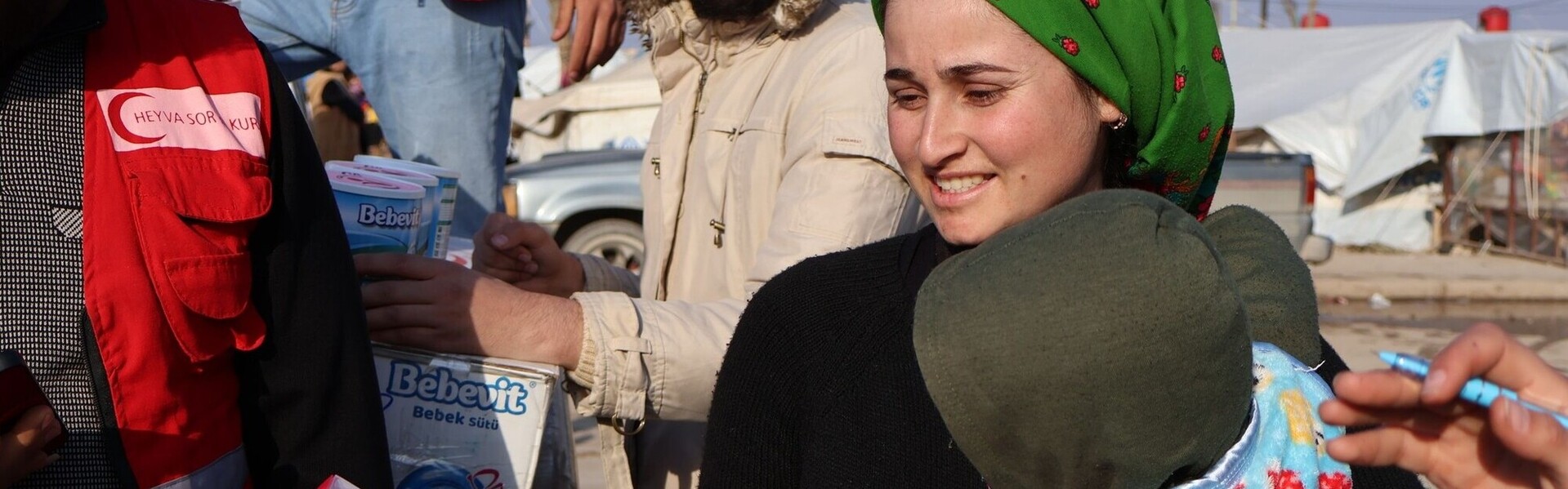 Eine syrische Frau erhält von einem Helfer Babynahrung und Spielzeug für ihr Kind