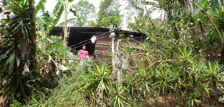 Eine Frau in Guatemala steht auf der Veranda ihres Holzhauses