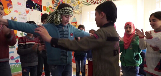 Im Libanon tanzen Kinder in einem Raum. Die Kinder sind aus Flüchtlingsfamilien.