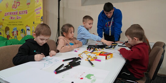Kinder sitzen an einem Tisch und malen Wunschzettel