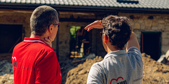 Zwei Helfer von AWO International stehen vor einem Bauprojekt in der Ukraine