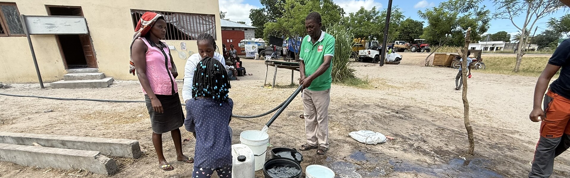 Nach dem Zyklon in Mosambik füllt ein Helfer sauberes Wasser in einen Eimer. Ein paar weitere Erwachsene und Kinder stehen daneben