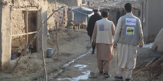 Zwei Mitarbeiter von Help gehen durch eine Wohngegend in Afghanistan