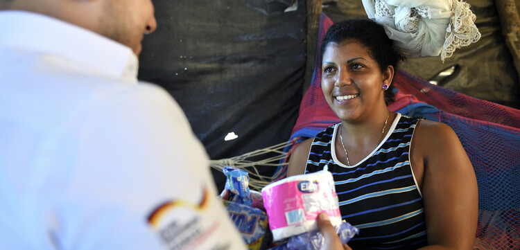 Ein Helfer der Malteser überreicht einer Migrantin aus Venezuela ein Hygiene-Paket Ein Helfer der Malteser überreicht einer Migrantin aus Venezuela ein Hygiene-Paket