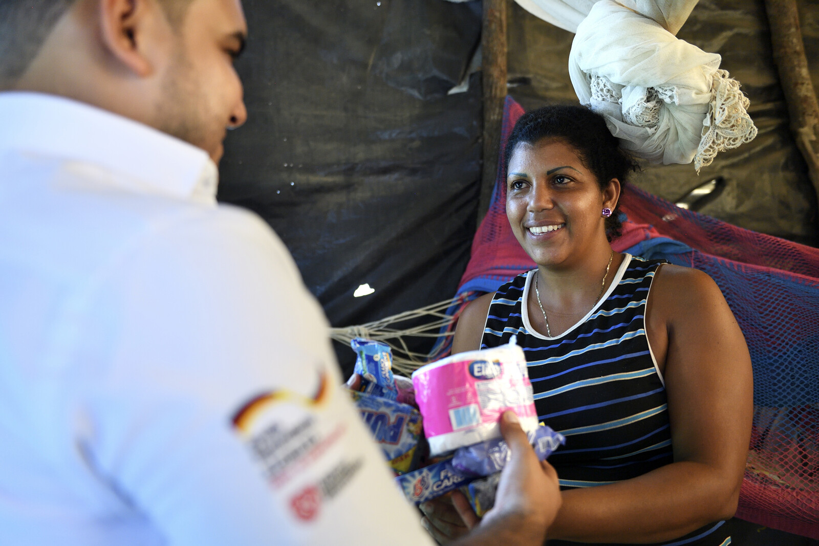 Ein Helfer der Malteser überreicht einer Migrantin aus Venezuela ein Hygiene-Paket