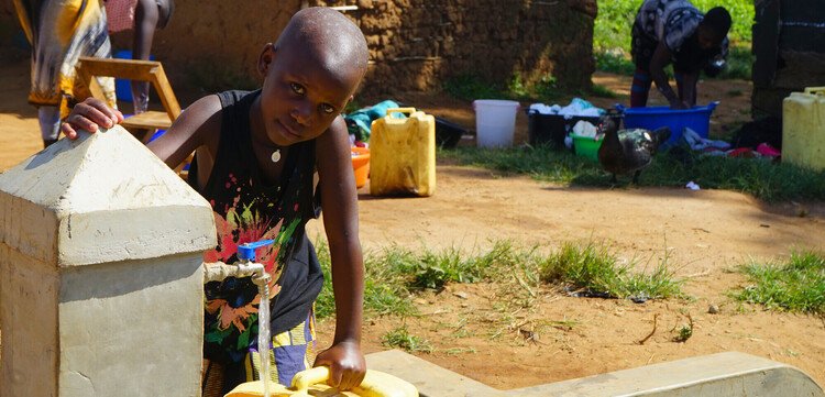 Ein Junge in Uganda füllt sich Trinkwasser in einen gelben Kanister ab Ein Junge in Uganda füllt sich Trinkwasser in einen gelben Kanister ab