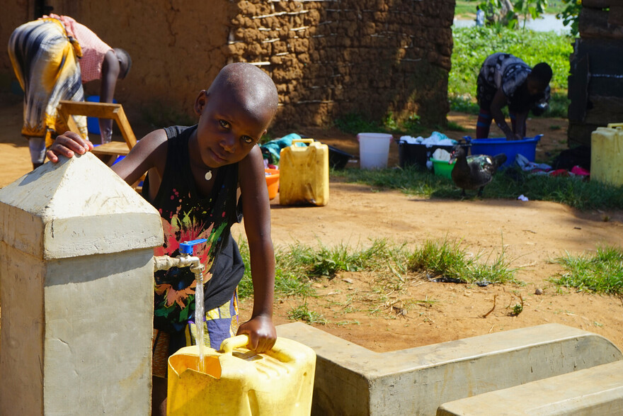 Ein Junge in Uganda füllt sich Trinkwasser in einen gelben Kanister ab Ein Junge in Uganda füllt sich Trinkwasser in einen gelben Kanister ab